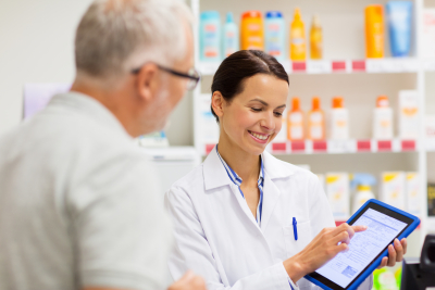 pharmacist and senior customer holding a tablet at pharmacy